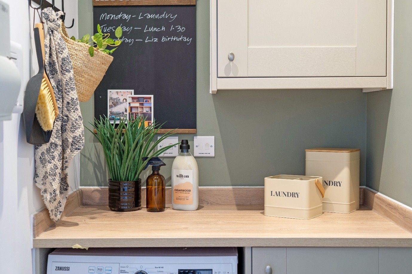 Utility room with a worktop above a washing machine, storage containers and cleaning products.