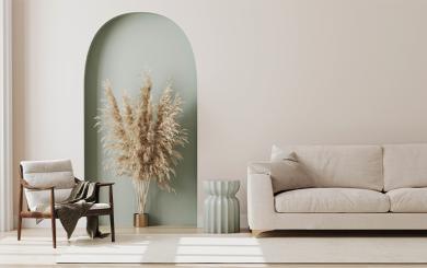 Interior of a minimalistic living room with beige coloured walls, sofa and armchair with a pastel green side table, accent wall and a large brown plant