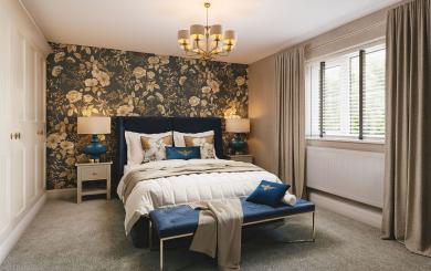 A stylish bedroom with an upholstered bed, floral feature wall, blue accents, bedside tables, and a window with open curtains.