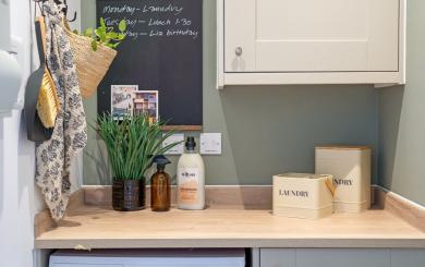 Utility room with a worktop above a washing machine, storage containers and cleaning products.