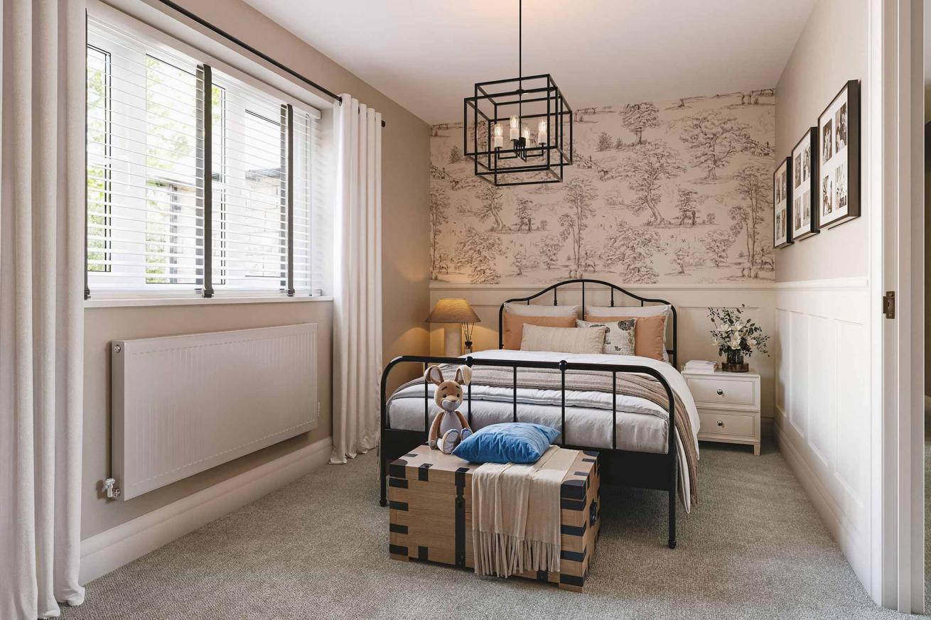 Cozy bedroom with a black metal bed frame, patterned wallpaper, and a trunk at the foot of the bed.