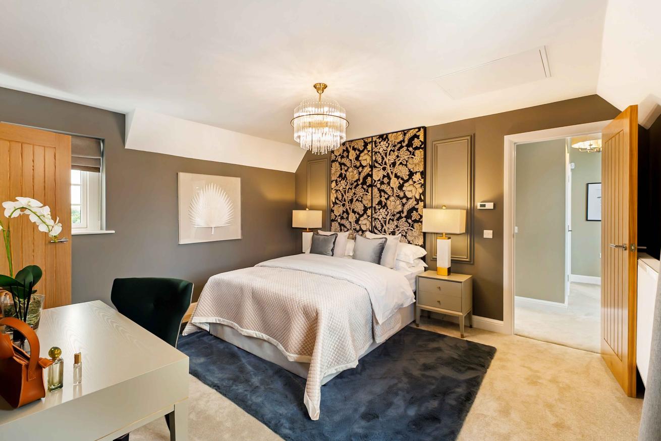 Modern double bedroom with a medium sized desk and chair. 