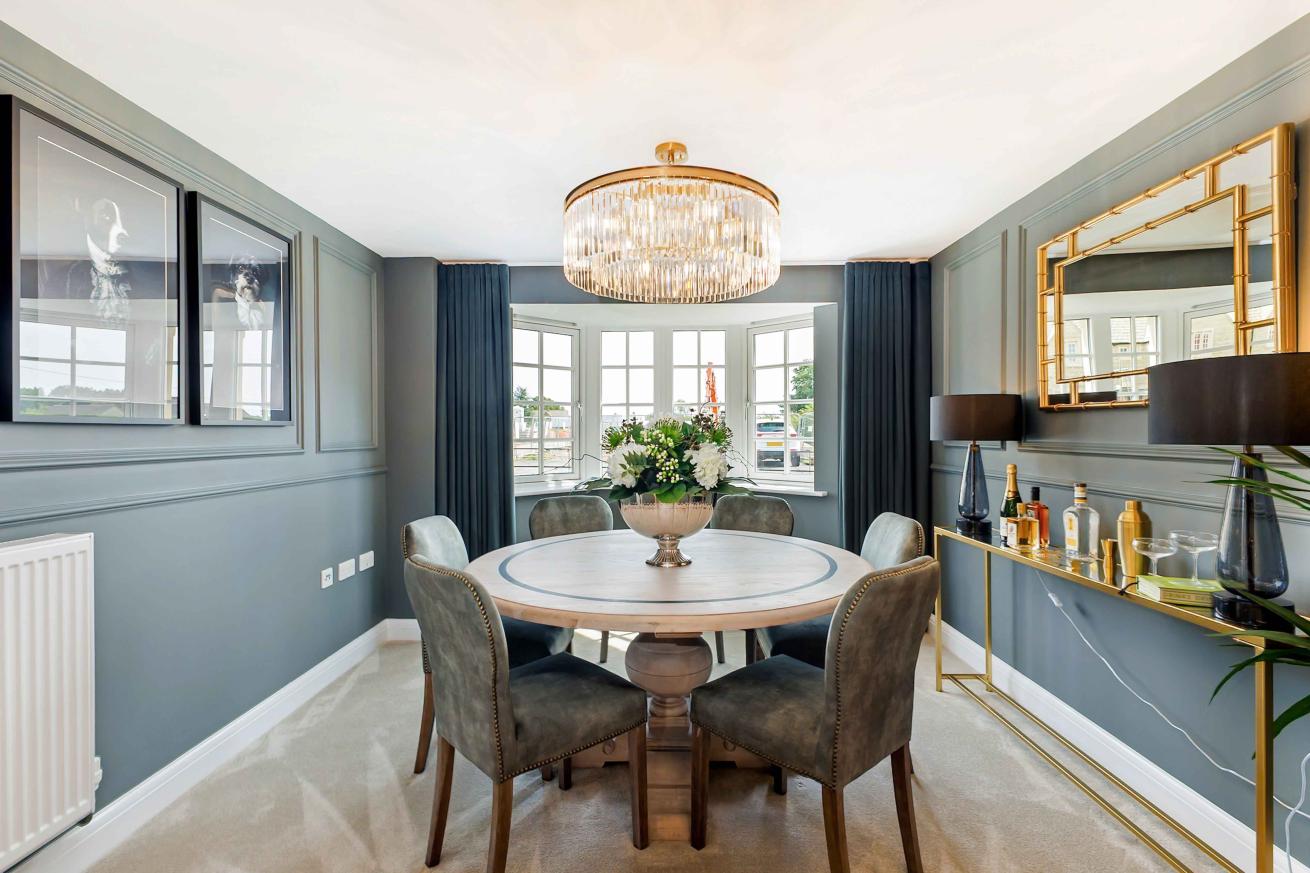 Well presented dining room with a round table decorated with flowers in it's centre
