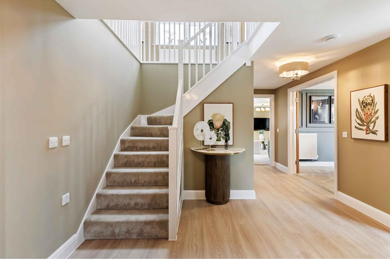 Modern hall with wooden floors, carpeted stairs and a small side table.  