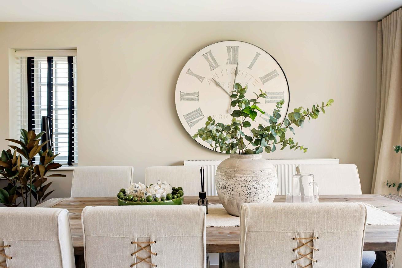 A wooden dining table decorated with a vase and flowers. 
