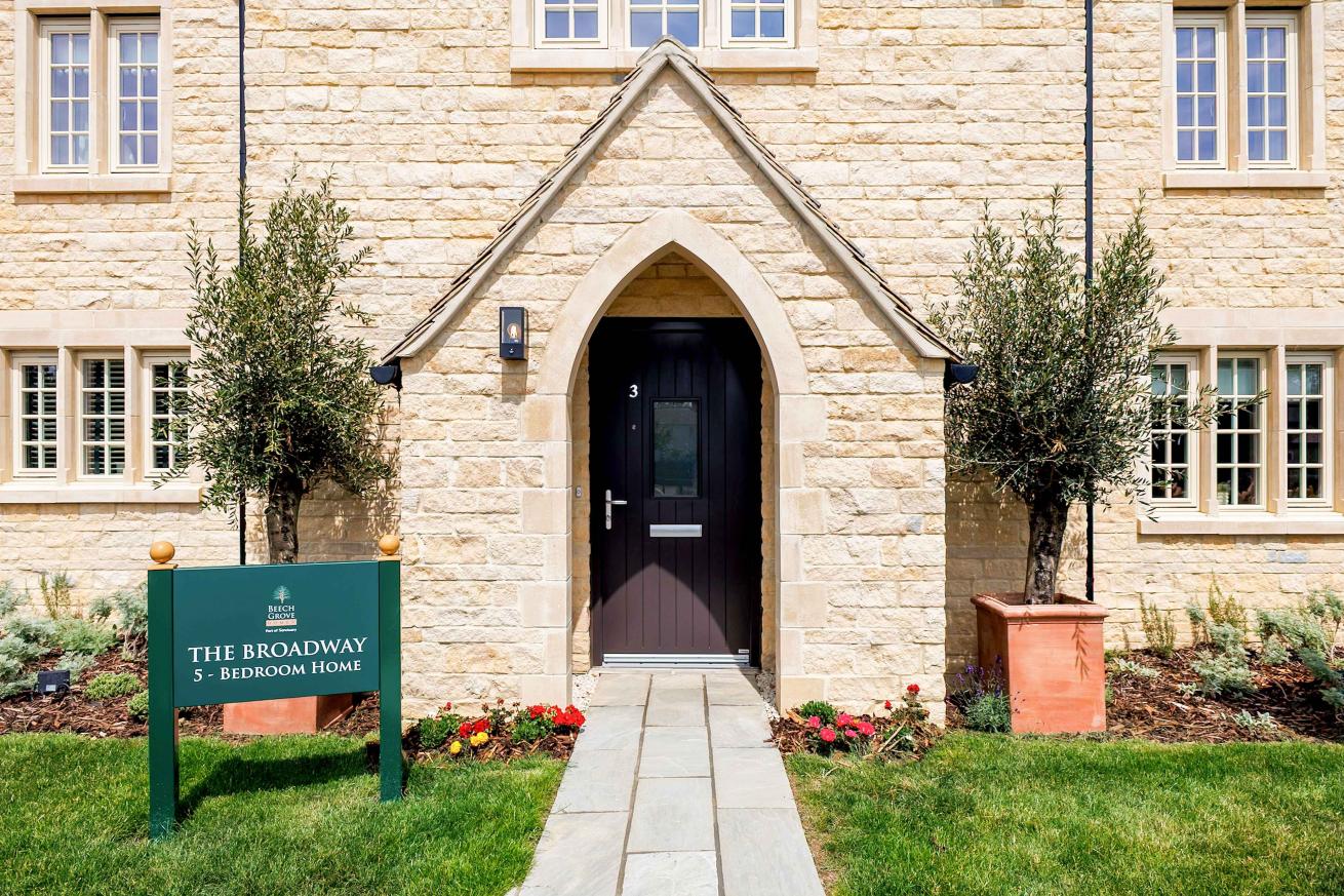 A light stone dethatched house, finished with a brown front door and grey pathway. 