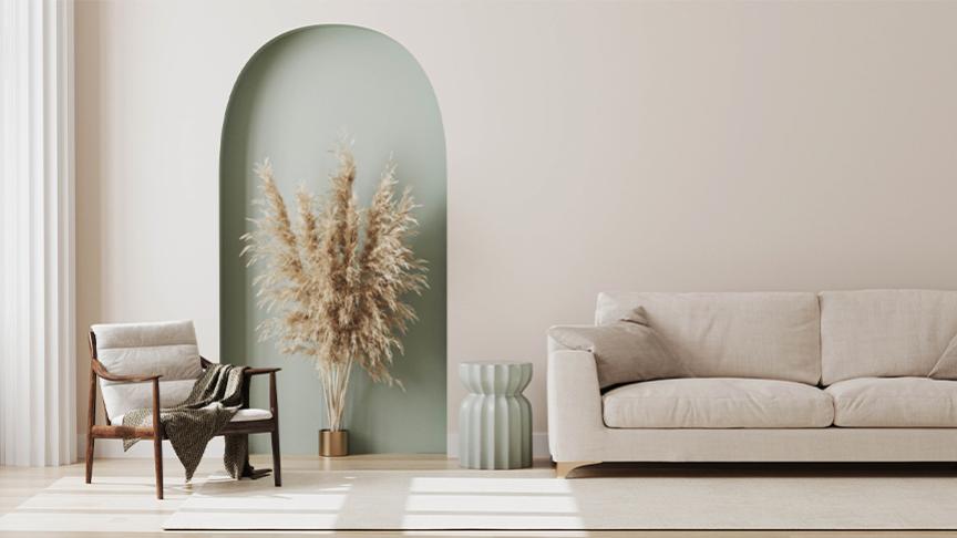 Interior of a minimalistic living room with beige coloured walls, sofa and armchair with a pastel green side table, accent wall and a large brown plant