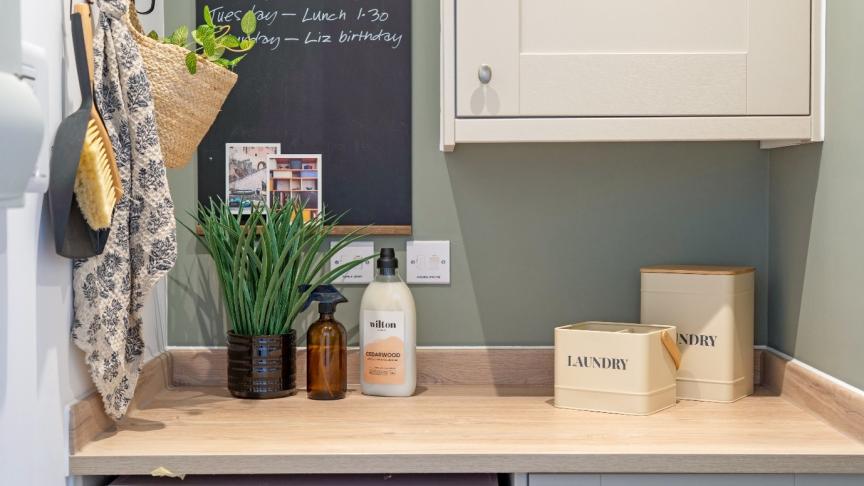 Utility room with a worktop above a washing machine, storage containers and cleaning products.