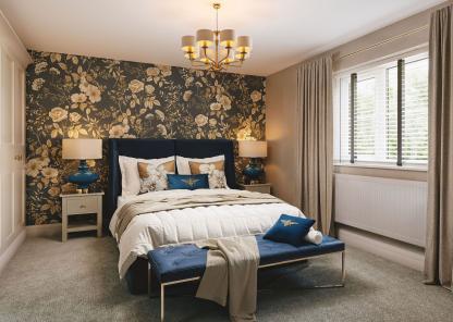 A stylish bedroom with an upholstered bed, floral feature wall, blue accents, bedside tables, and a window with open curtains.