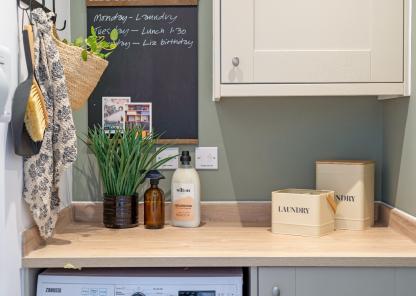Utility room with a worktop above a washing machine, storage containers and cleaning products.